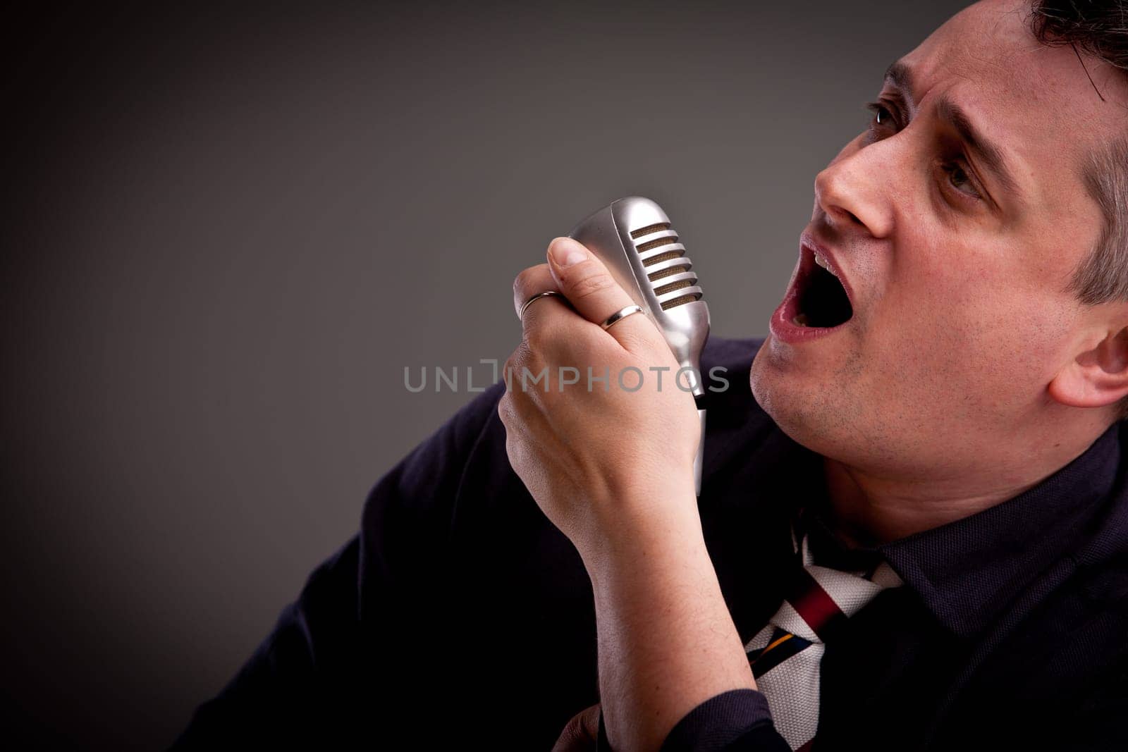 a fifties style singer is singing with an old microphone in his hand
