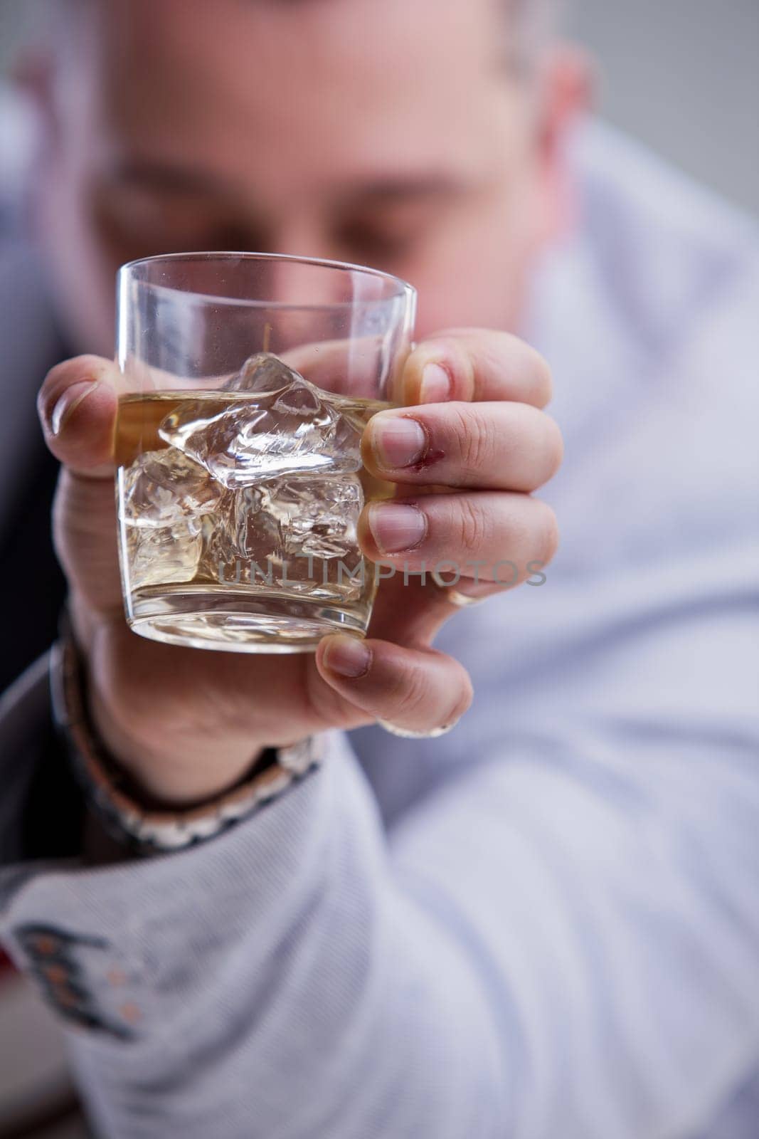 heavy drinker shows a glass of white wine on the rocks