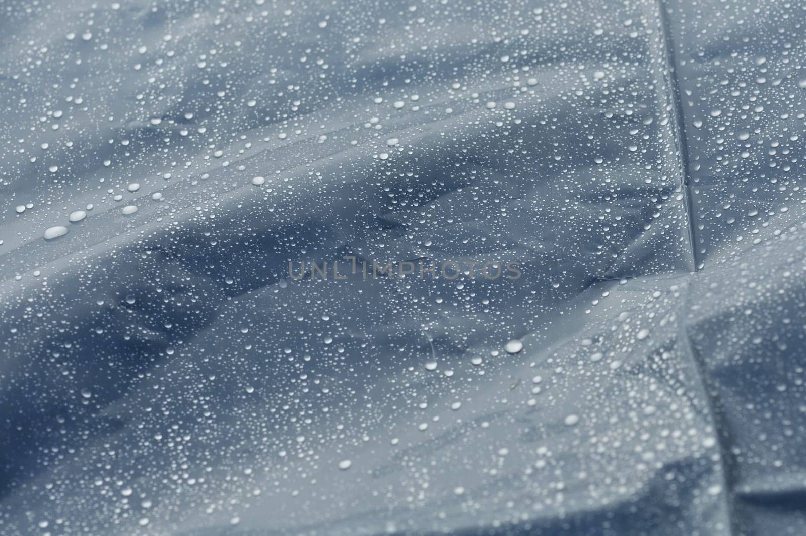 Rain drops on bumpy plastic surface abstract autumn weather macro background. Selective focus.