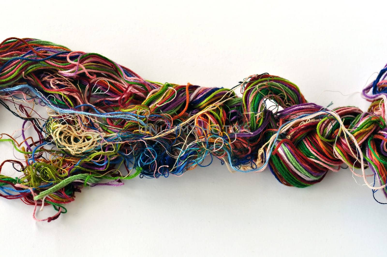 Tangled colorful sewing threads on white background.