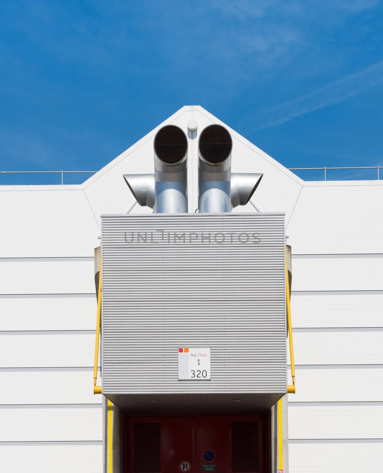 exhaust pipes above the entrance of a large industrial building