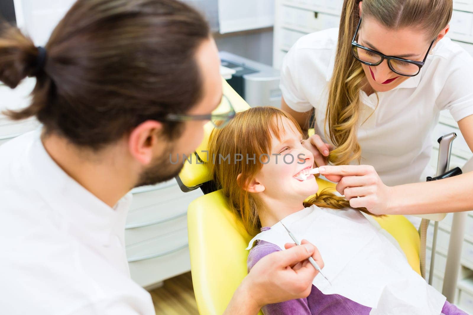 Dentist and assistant treat patient in dental practice