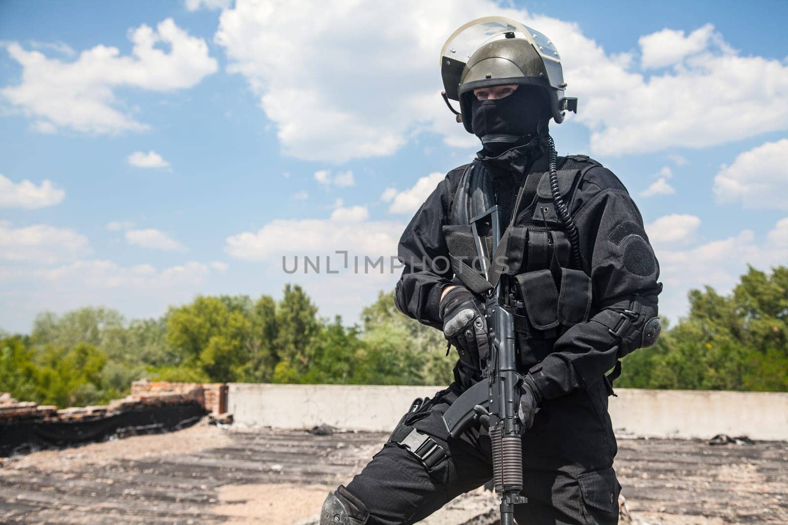 Spec ops soldier in black uniform and face mask with his rifle