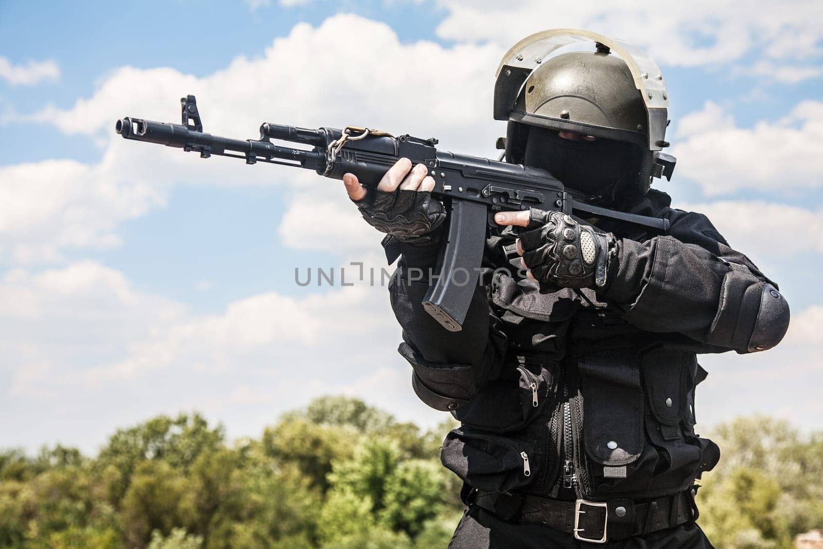 Spec ops soldier in black uniform and face mask with his rifle