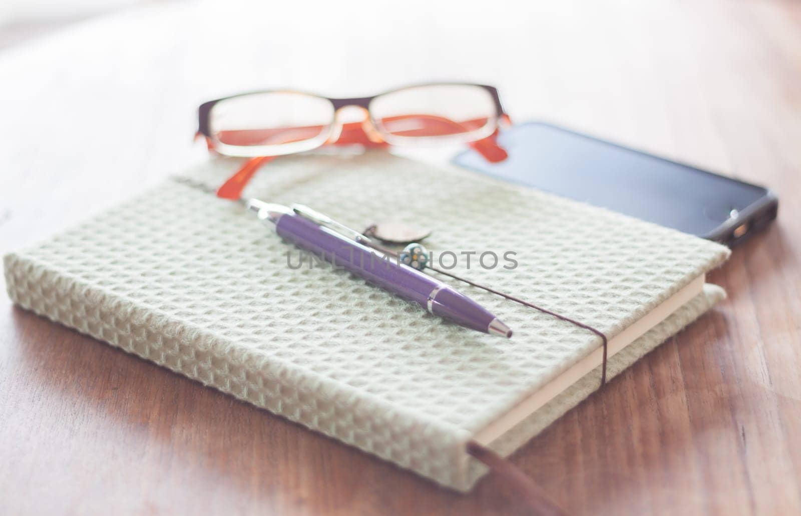 Notebook and pen with eyeglasses on wooden table, stock photo