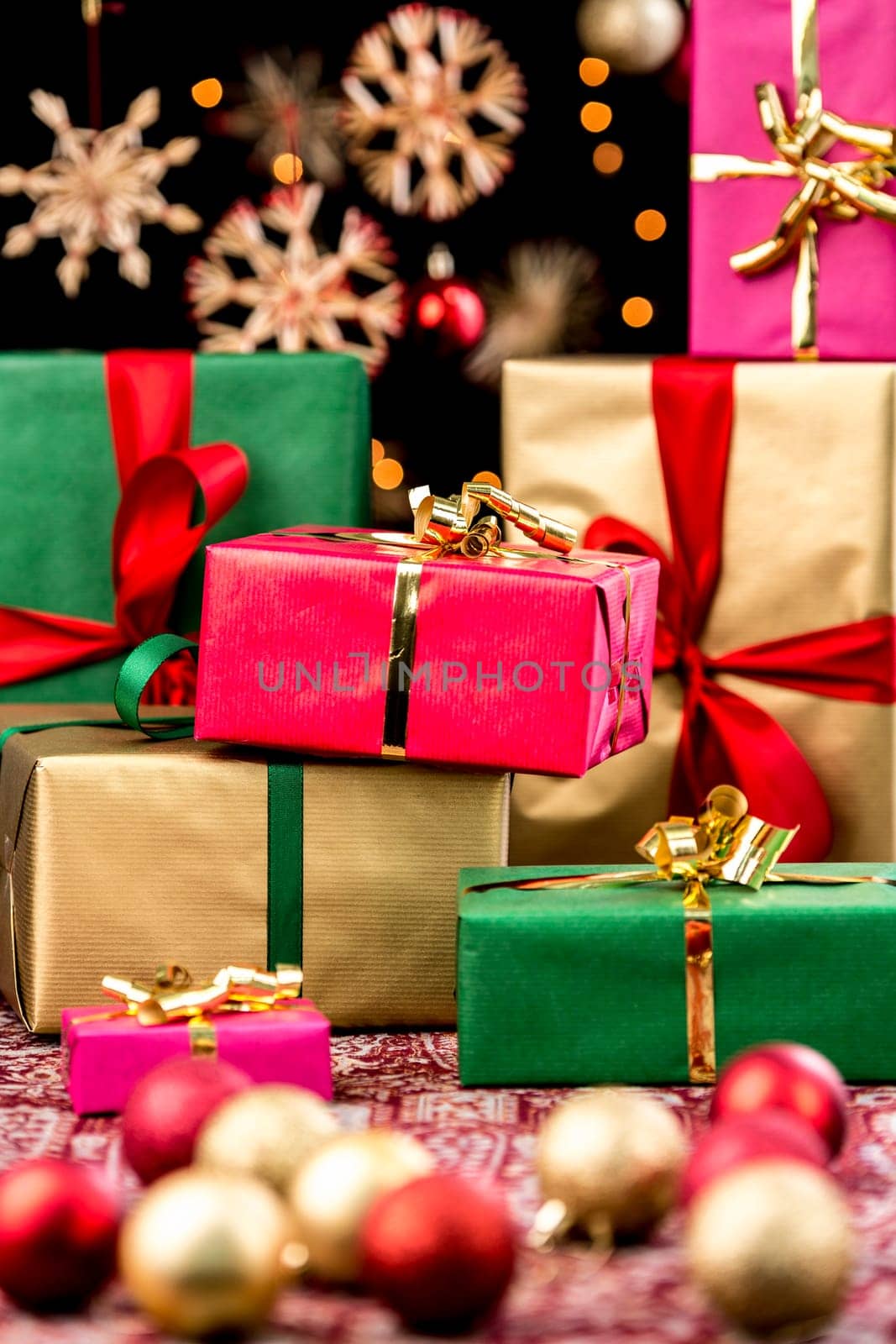 Christmas presents in red,green,gold and magenta. Blurred shapes of sparkling baubles in front and back. Orange twinkles and hazy stars against pitch black. Seasonal background.