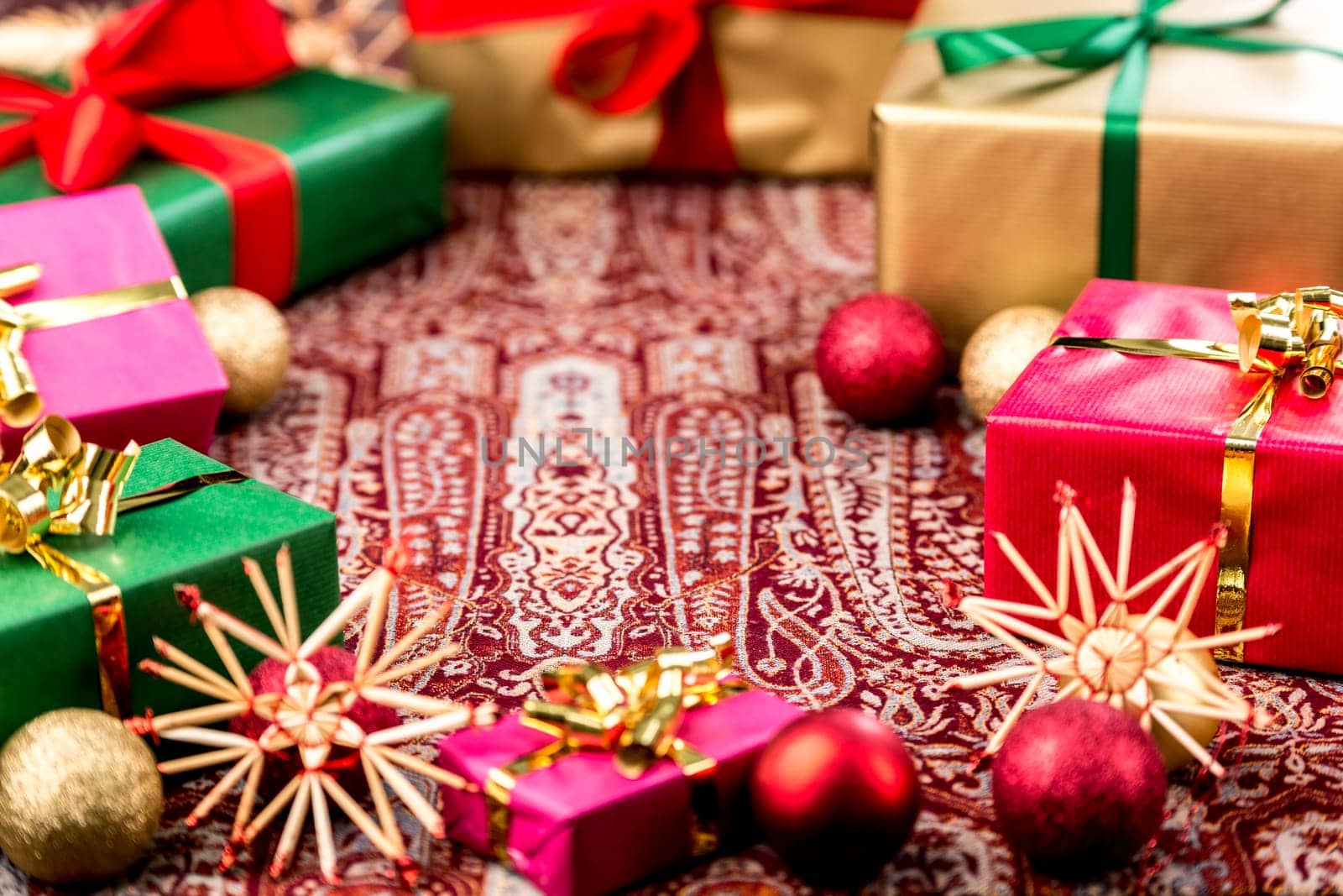 Circular arrangement of plain Christmas presents wrapped in green,red,magenta and gold. Depth of field cutting across the crimson box. Tightly-framed with central void. Circular arrangement of monochrome Christmas parcels wrapped in green,red,magenta and gold. Depth of field runs across the high red box. Bold cut with central emptiness. Background for the big festival.