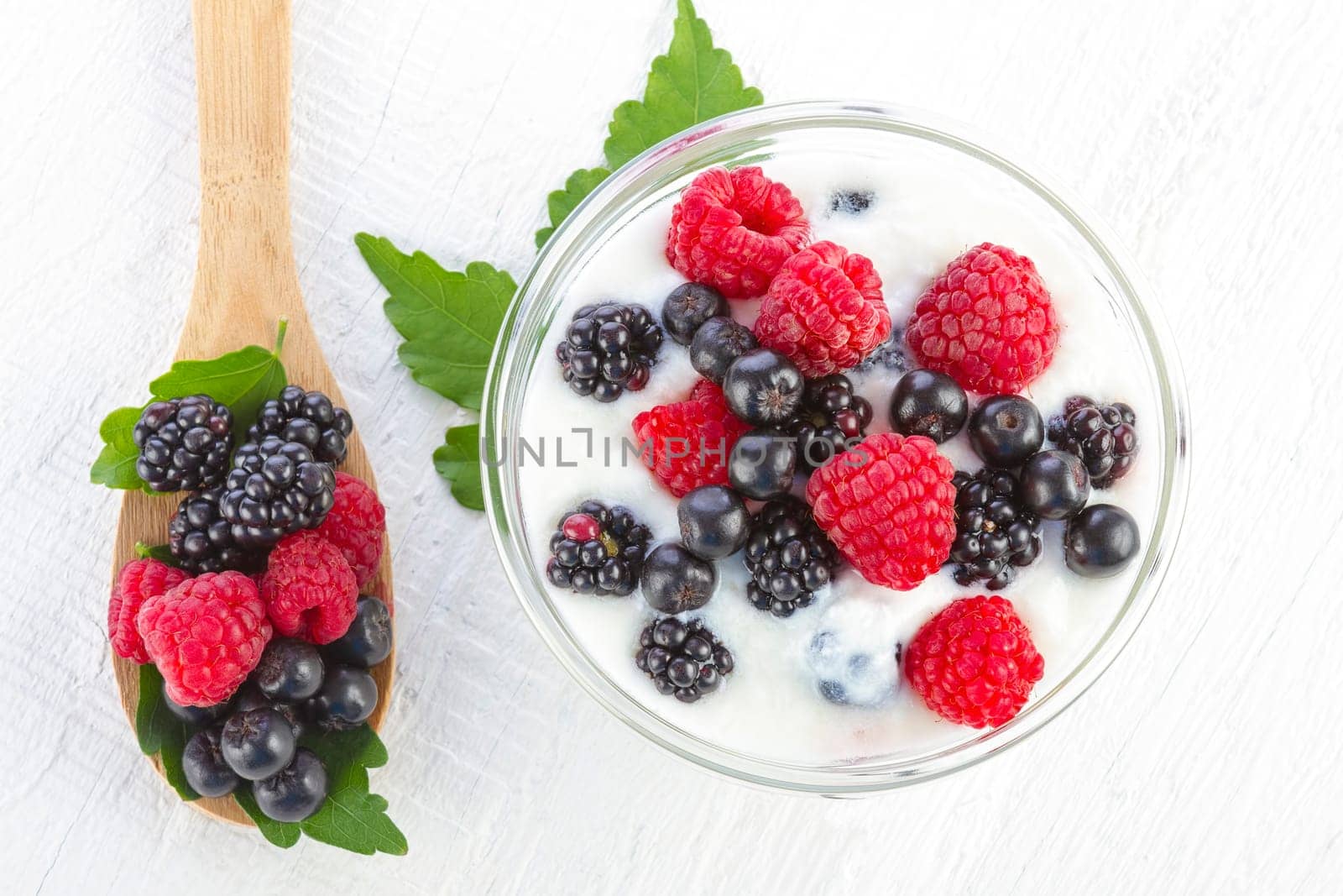Yogurt with berries in wooden bowl on wooden background