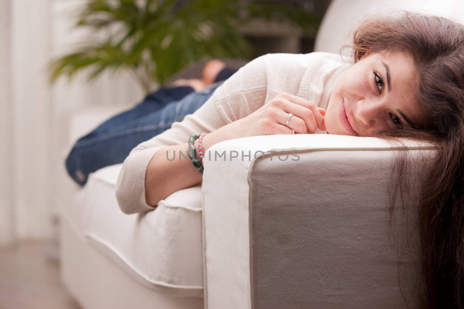 this girl lies on the sofa and smiles because she's waiting for something good and satisfying and she's happy and relaxed and maybe falling in love or maybe she won lotto or bingo