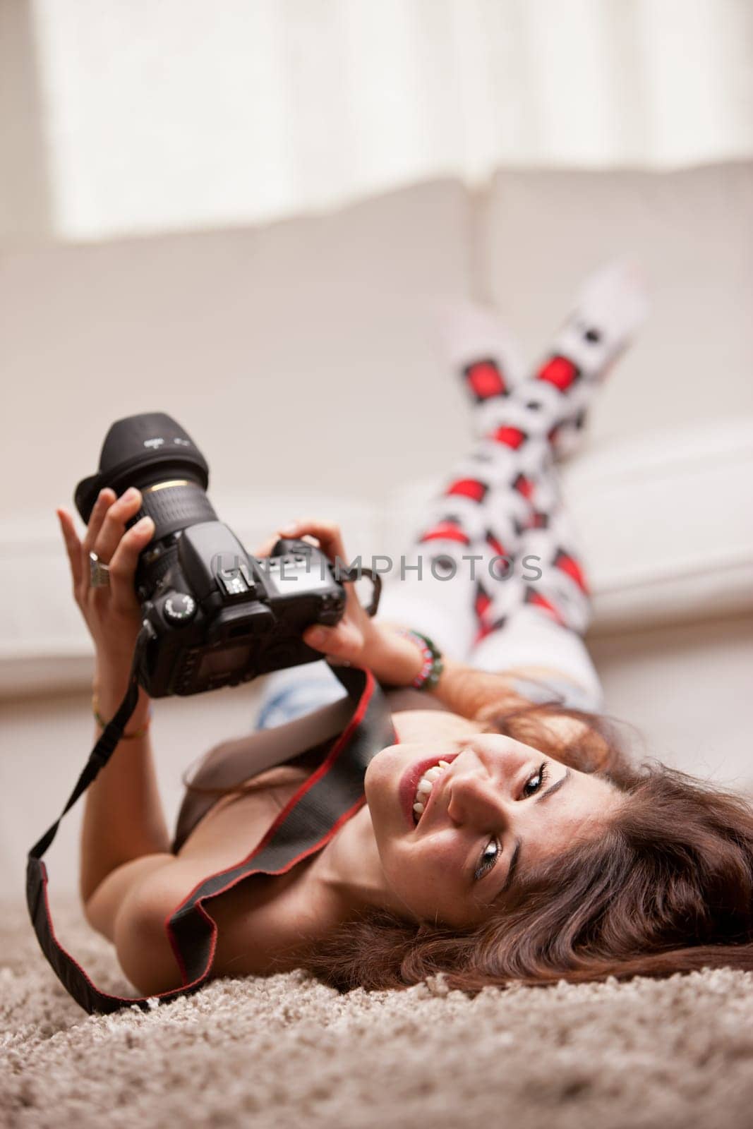 this beautiful smiling sexy nice young girl has a really big DSLR camera reflex in her hands and maybe she's watching pictures or taking them who knows
