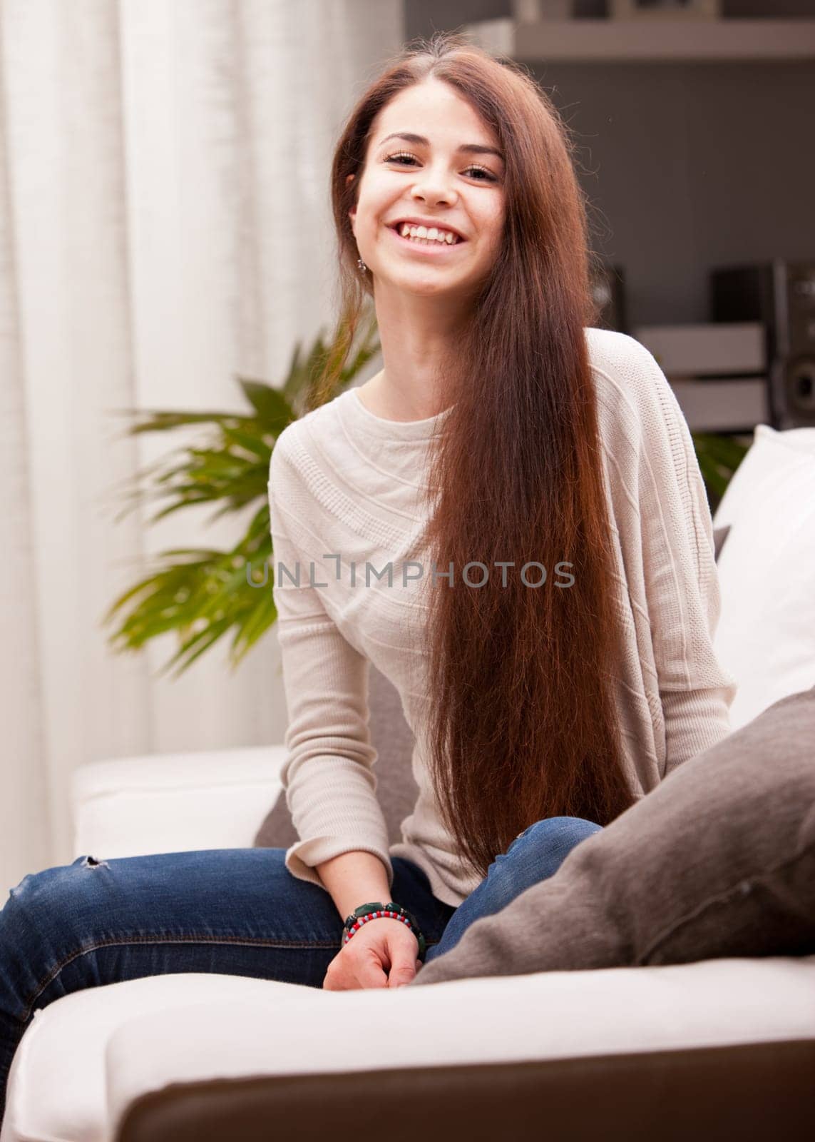 a young happy smiling pretty girl on a sofa with VERY long brown hair