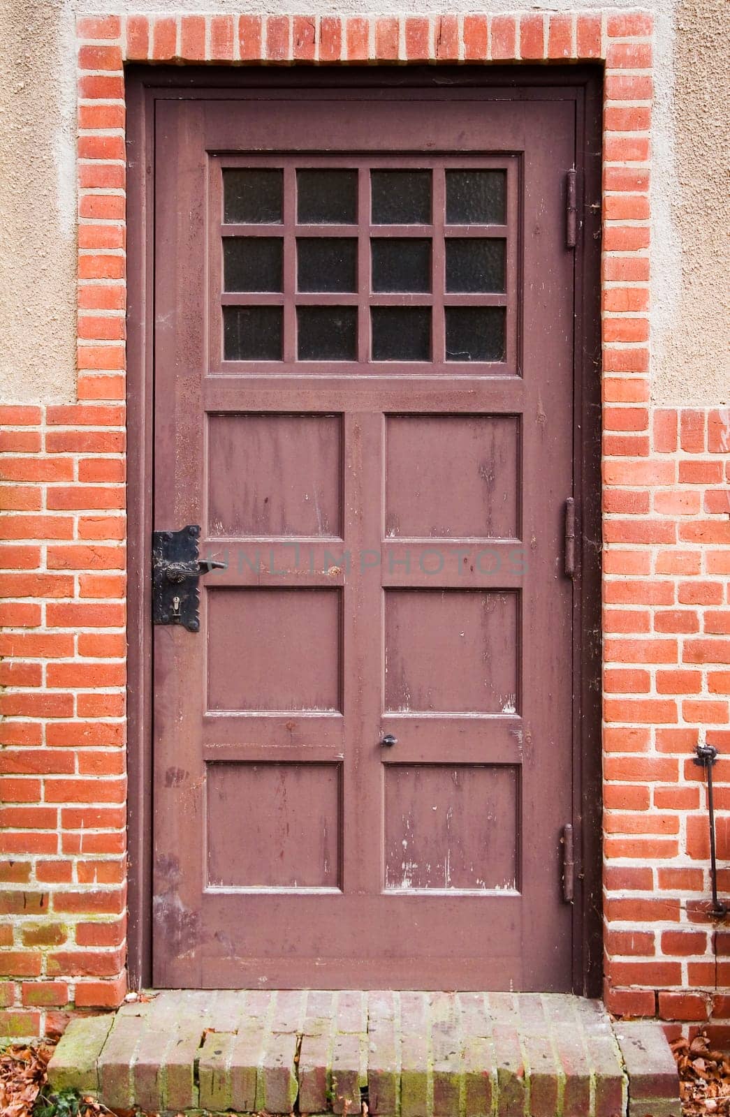 frontal view of an old brown cassette door with step in brick facade
