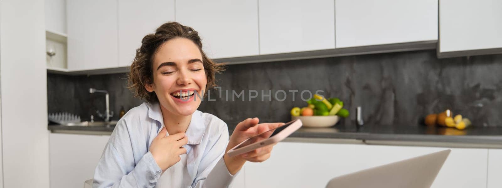 Portrait of beautiful woman at home, holding smartphone, online shopping from mobile phone app.