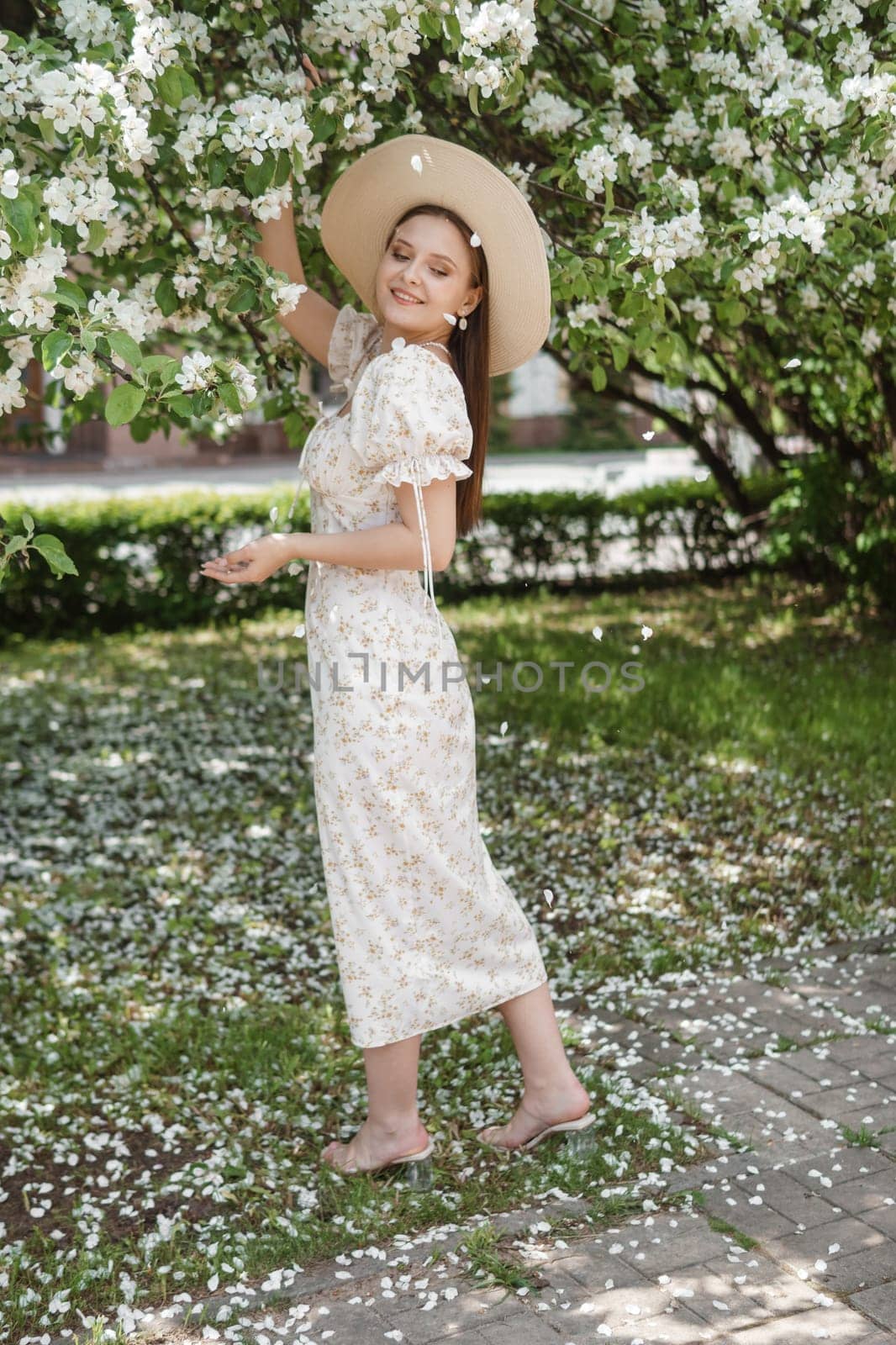 An attractive long-haired woman walks in the spring in the park of blooming apple trees. by Annu1tochka