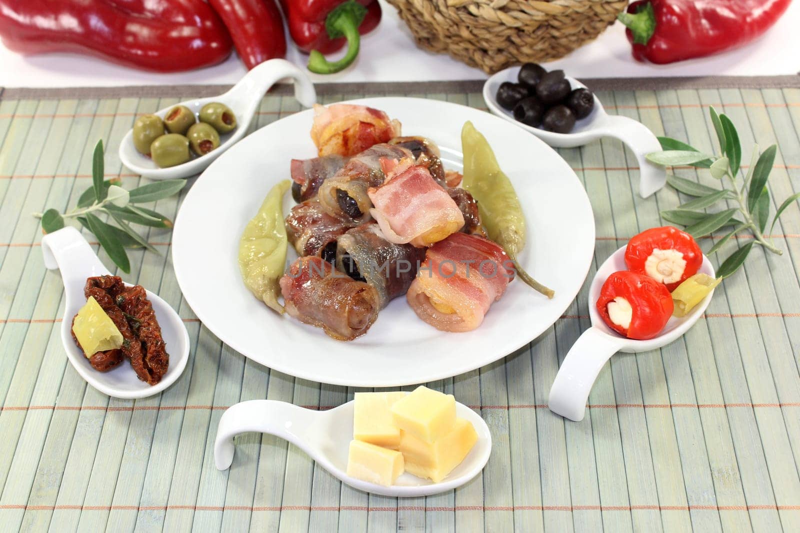 various tapas in serving spoons on a wooden mat
