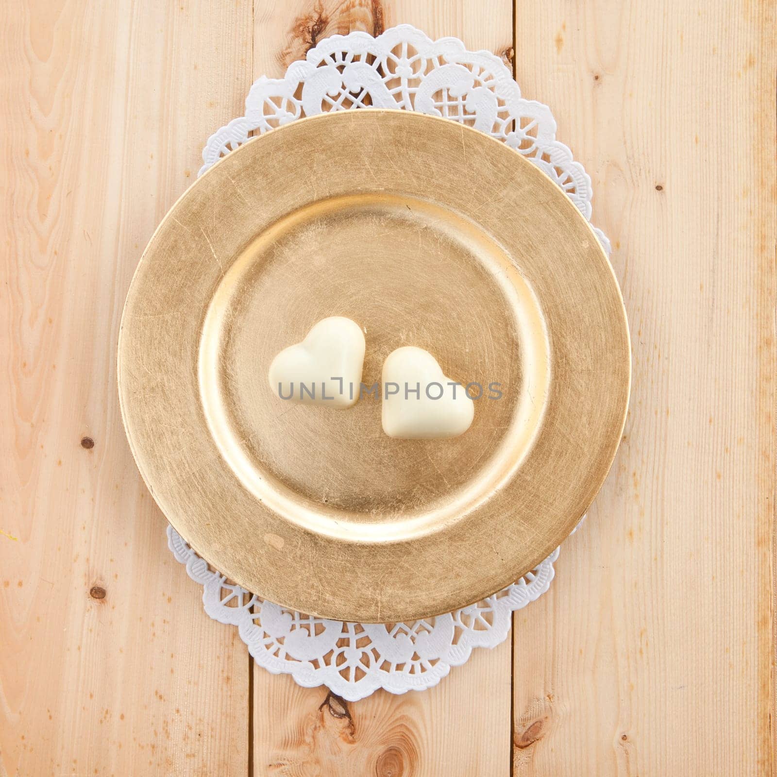 Two hearts of white chocolate on a golden plate