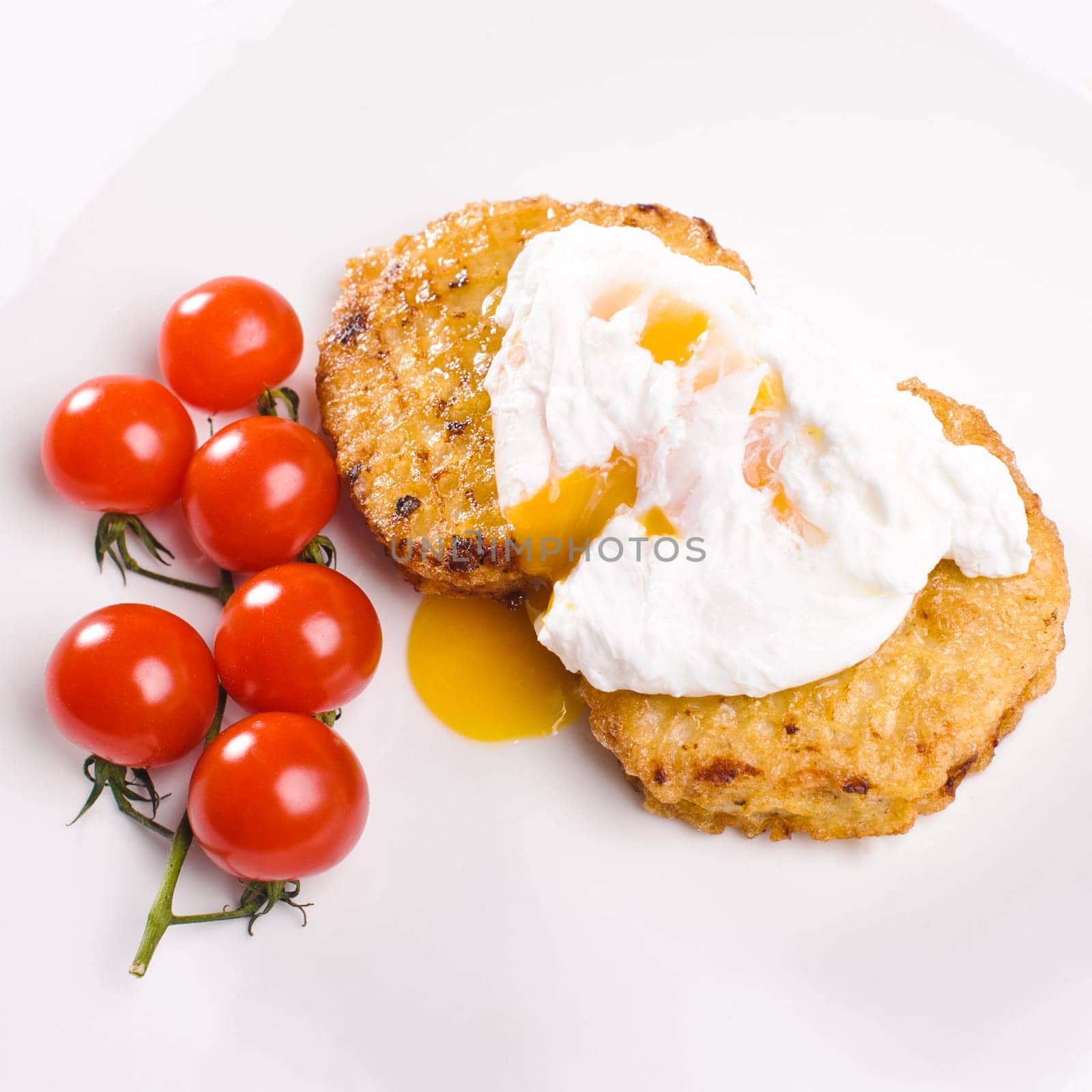 Two cutlets with branch of small tomatos and egg on white plate