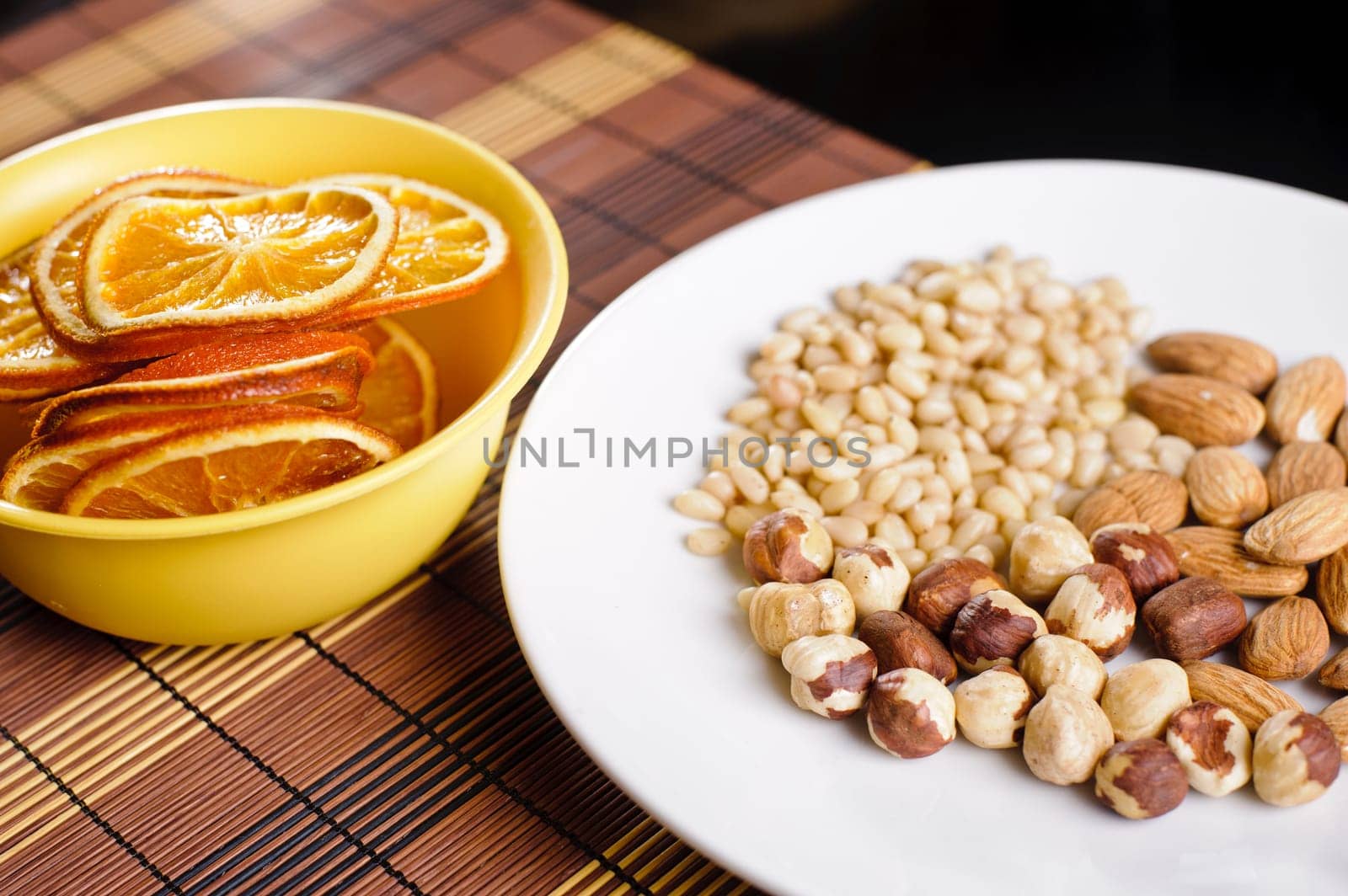 Mixed nuts on a white plate and dried orange