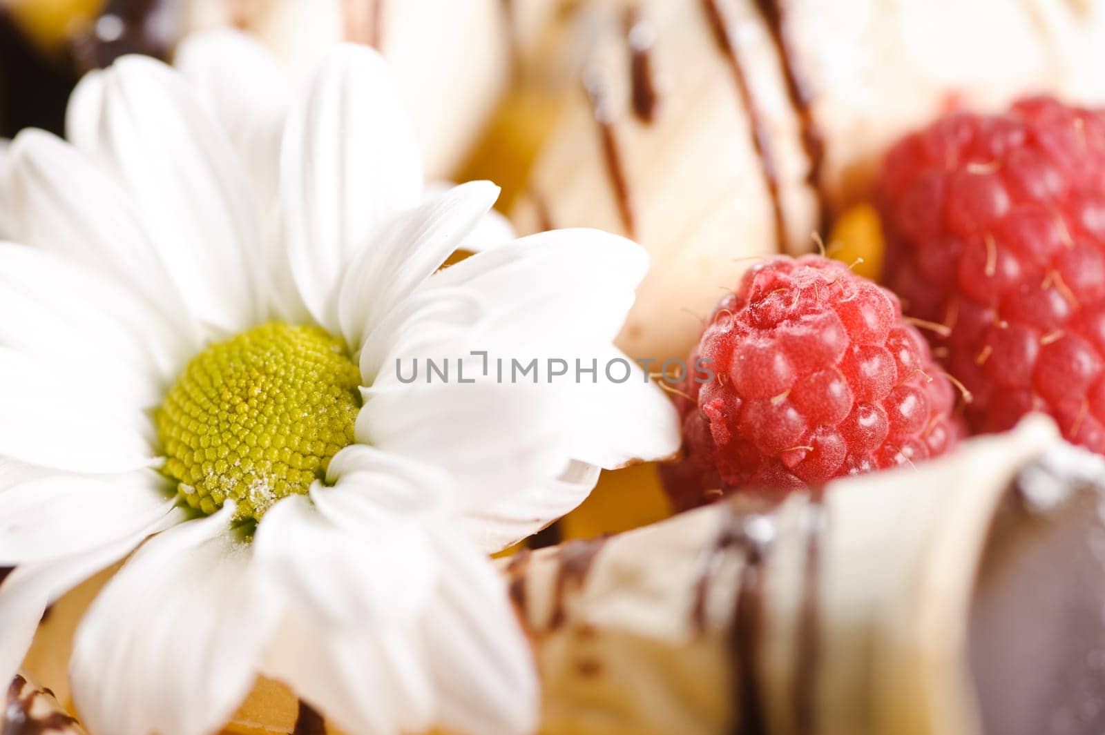 Piece of cake on plate with berries and fruits and camomile