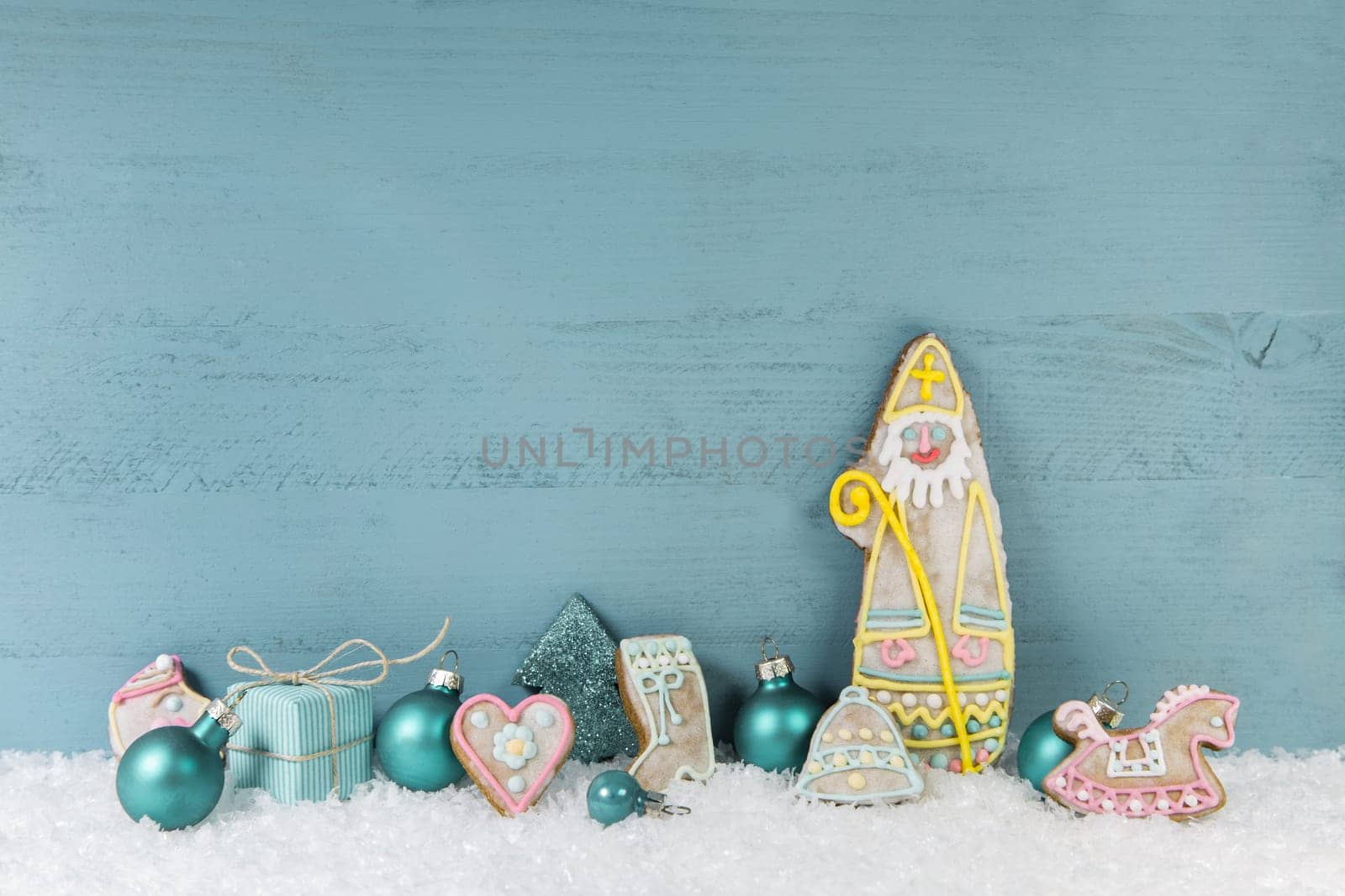 Wooden light blue christmas background. Xmas decoration in blue, turquoise, white and yellow with a santa of gingerbread.