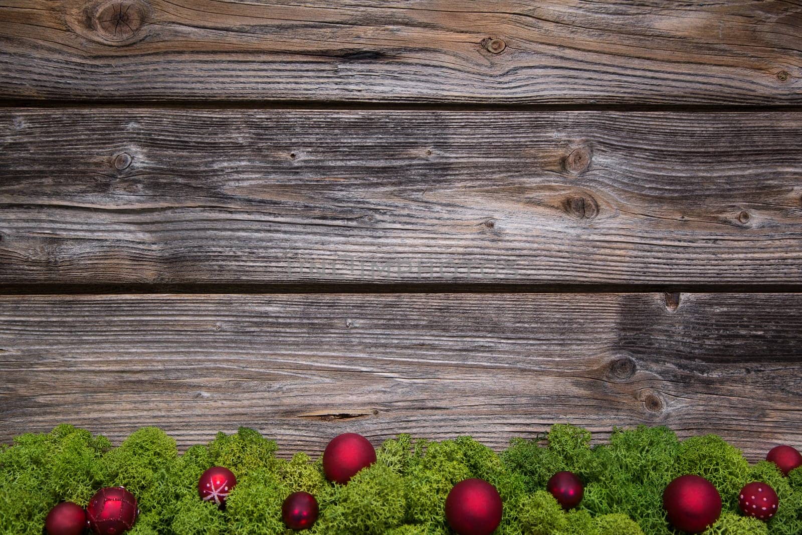 Wooden christmas frame with green moss and red balls on the frame.