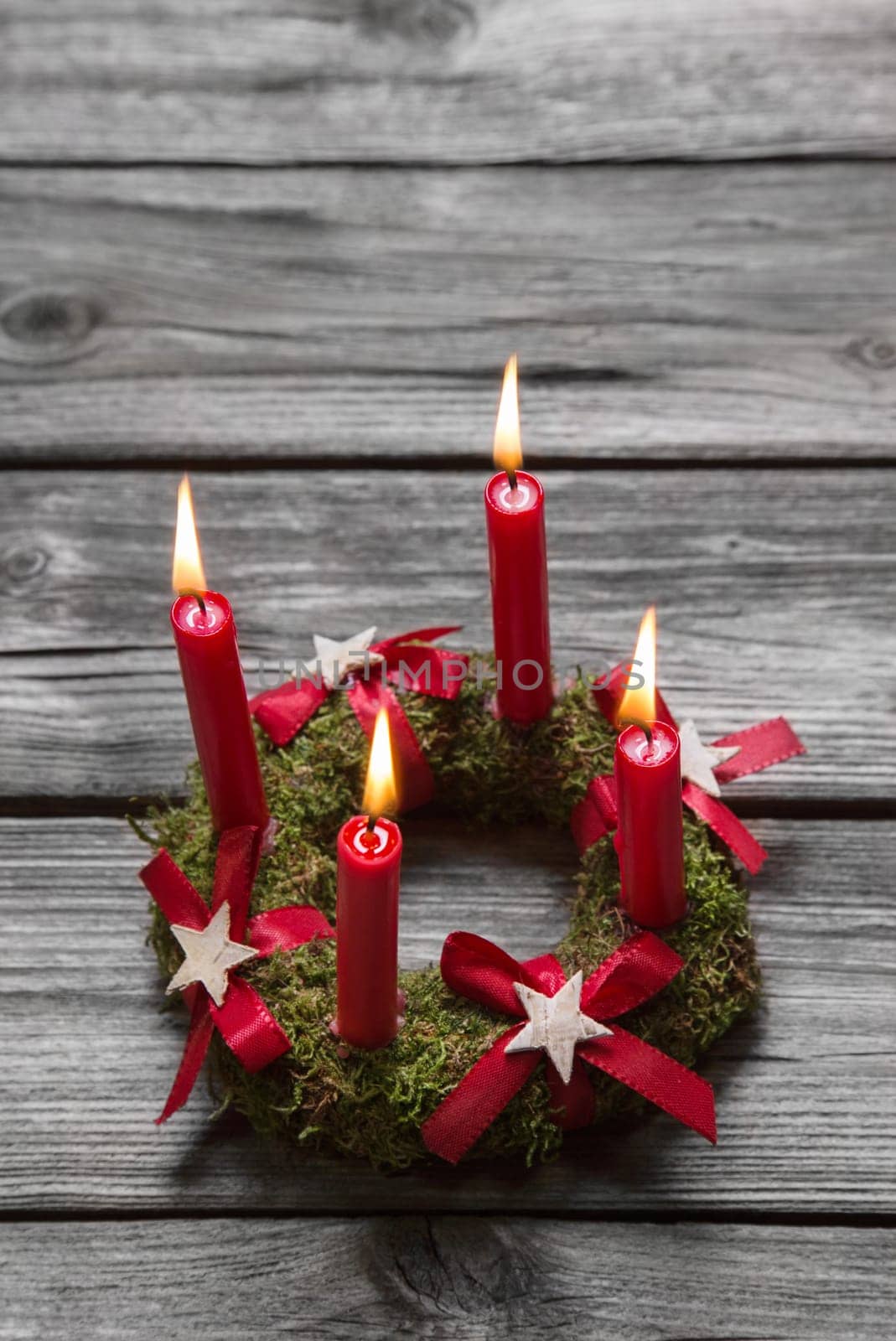 Greeting card with four red burning advent candles on wooden grey background.