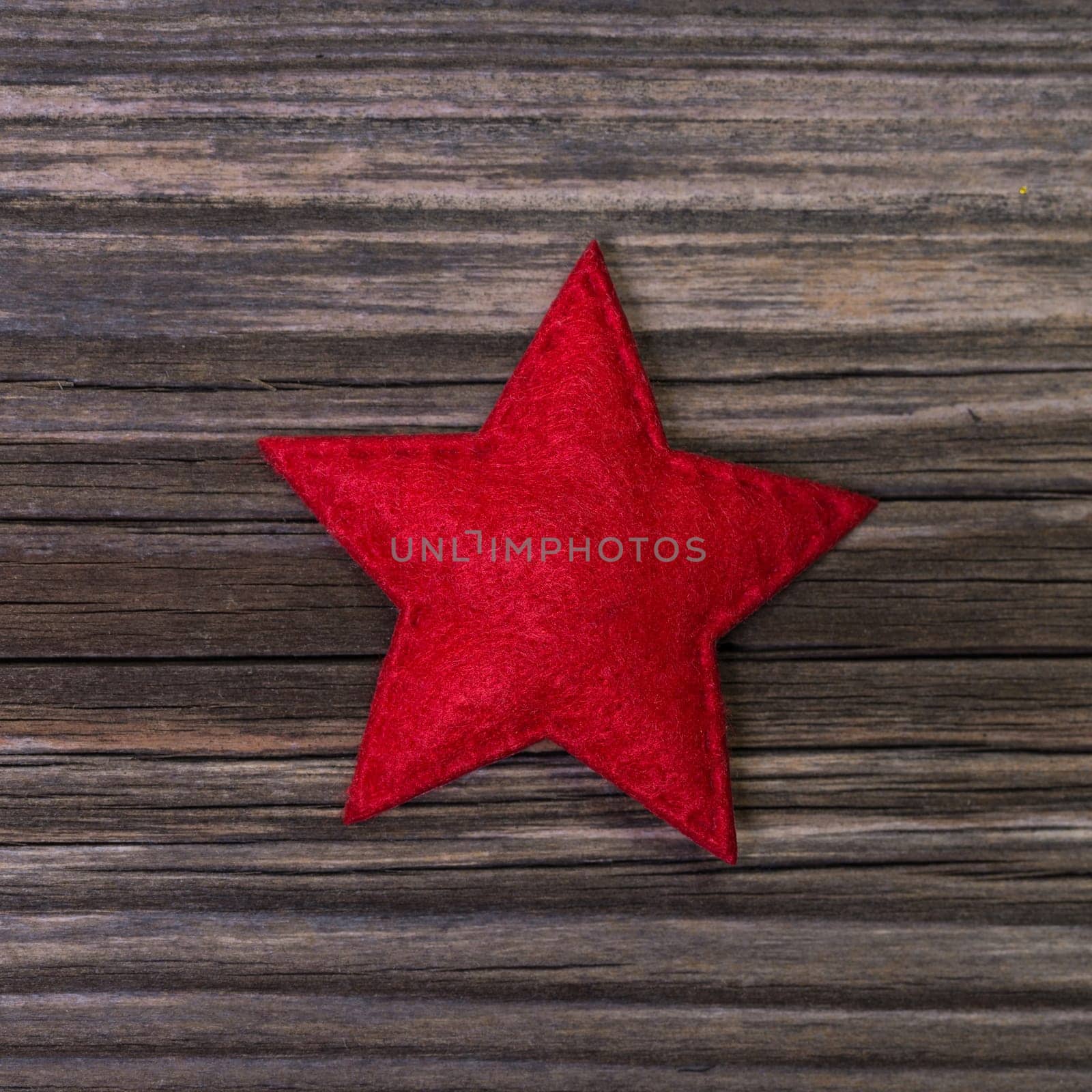 One red christmas star of felt on wooden background for decoration.
