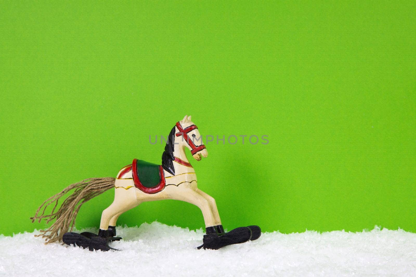 Wooden christmas horse on a green and white background for a greeting card.