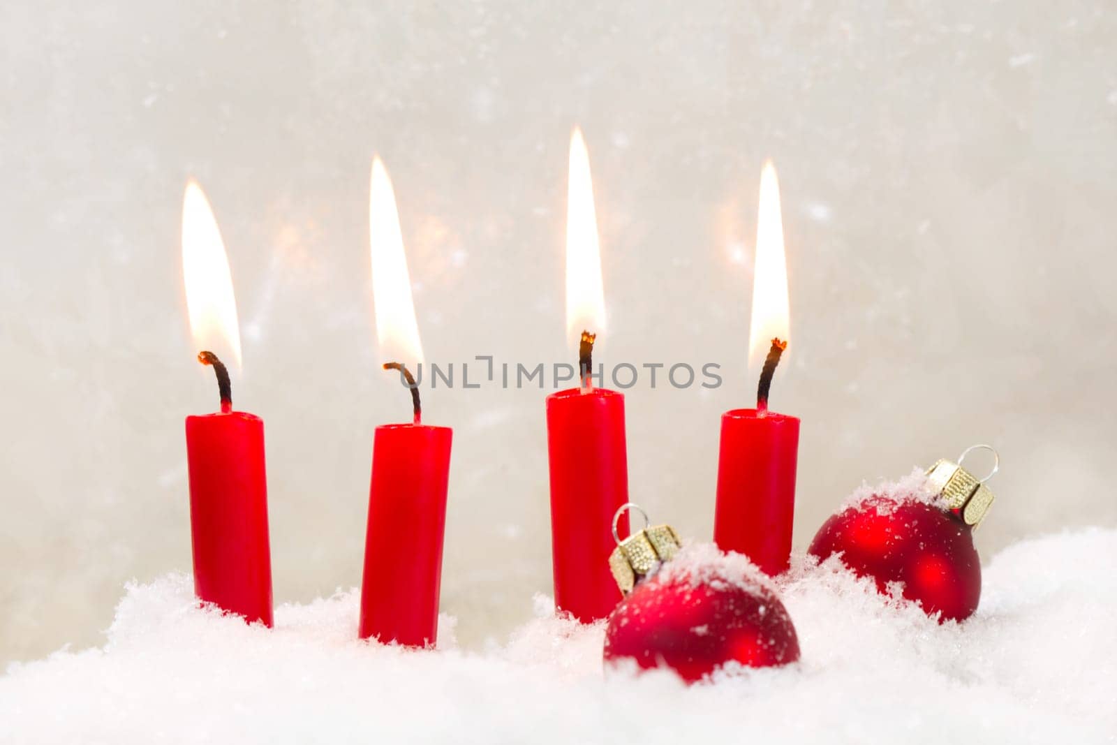 Four burning red candls with christmas ball