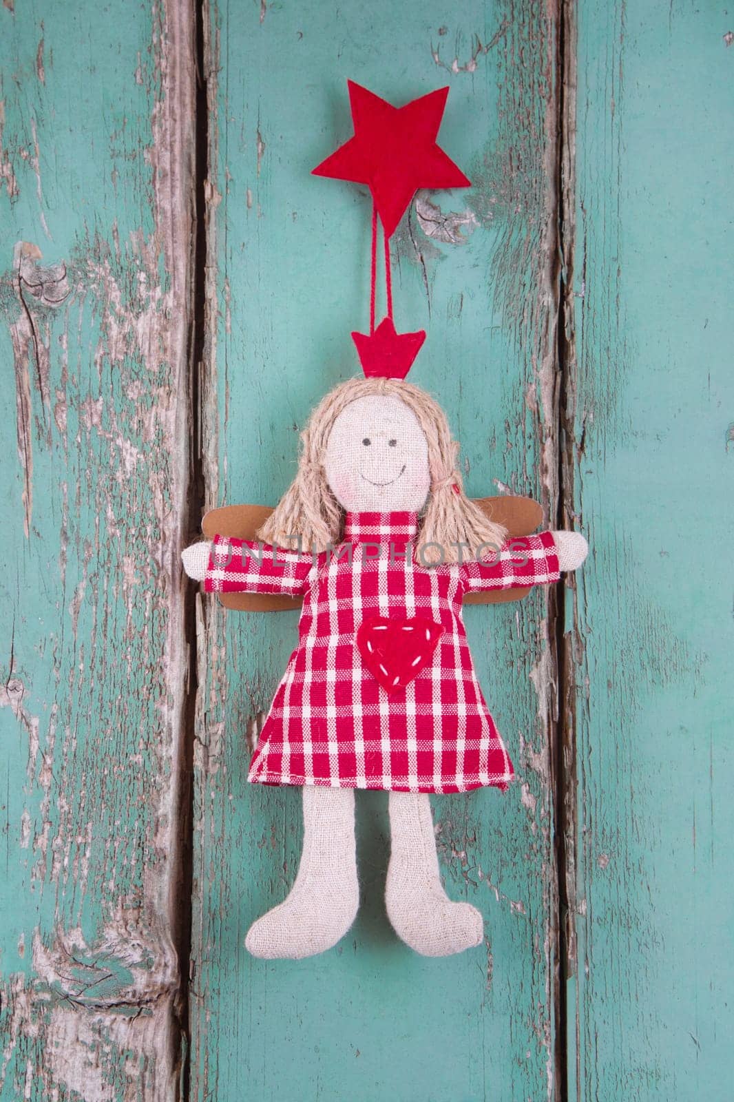 Sewn angel doll hanging on turquoise wooden background for christmas