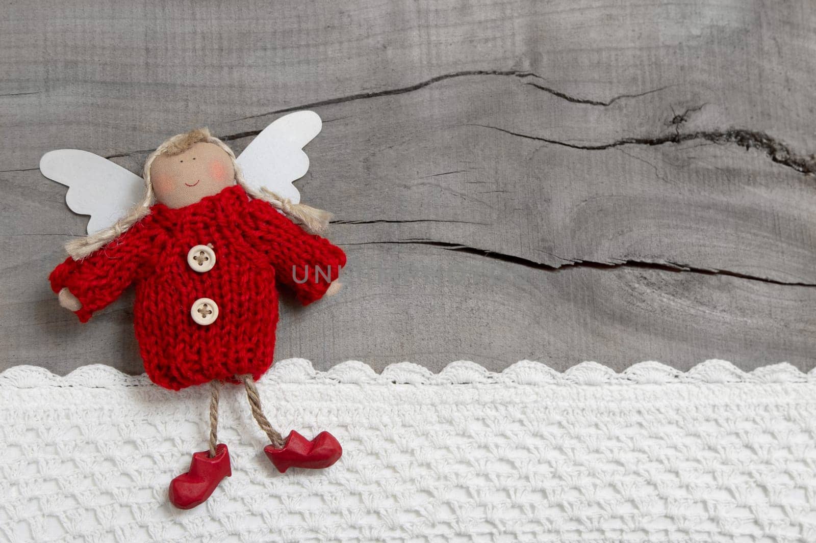 Red christmas or guardian angel on grey wooden background for a greeting card
