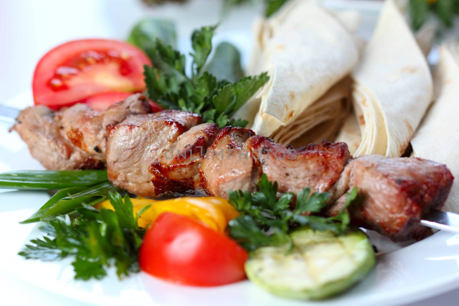 shish pork kebab with greens and vegetables (closeup, selective focus)