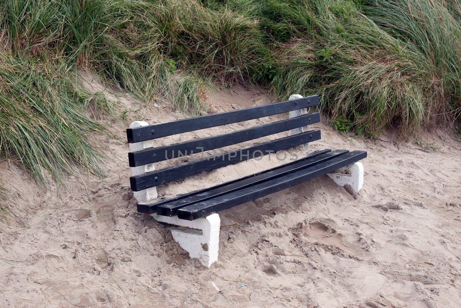 bench covered in sand from the winter storms in Ireland