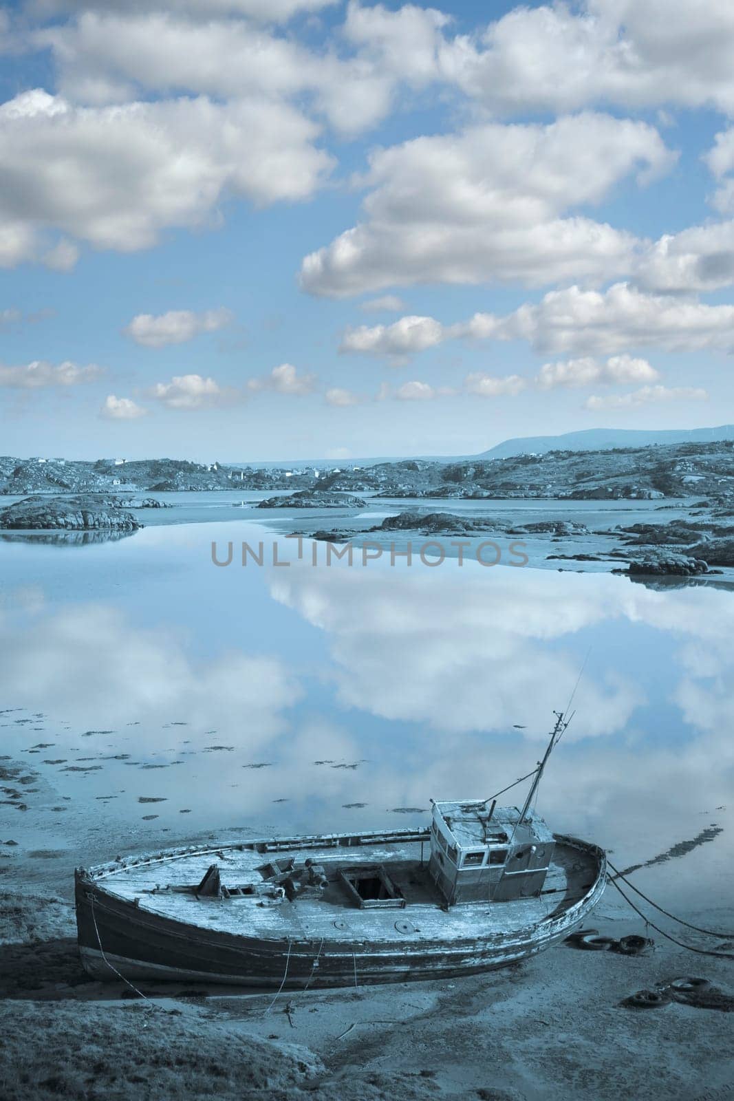 old fishing boat beached on a coastal beach in county Donegal, Ireland in blue tone