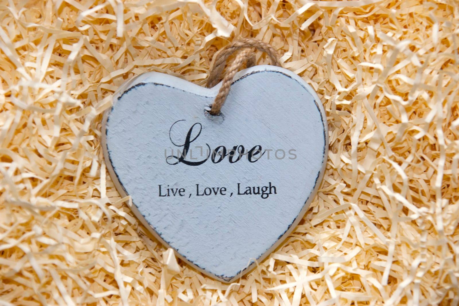 single grey wooden love heart in a love nest made of straw