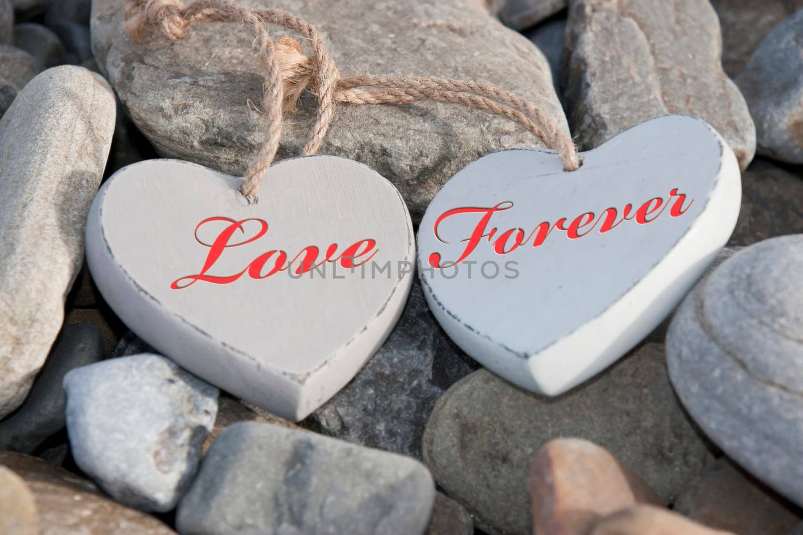 two wooden love hearts on the rocks of a beach