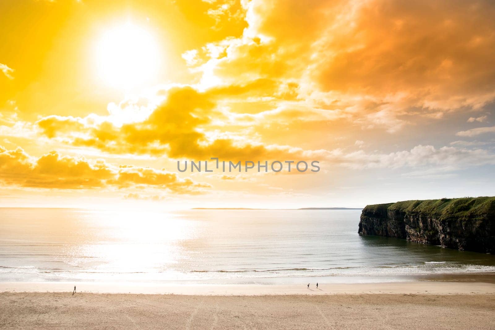 tourists walking the Ballybunion beach near cliffs in county Kerry Ireland on a beautiful summers day