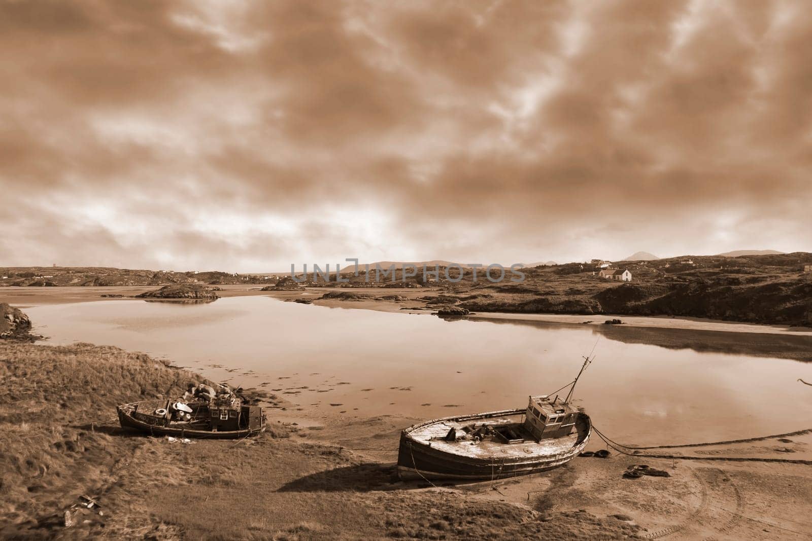 two old fishing boats beached on a coastal beach in county Donegal, Ireland in sepia