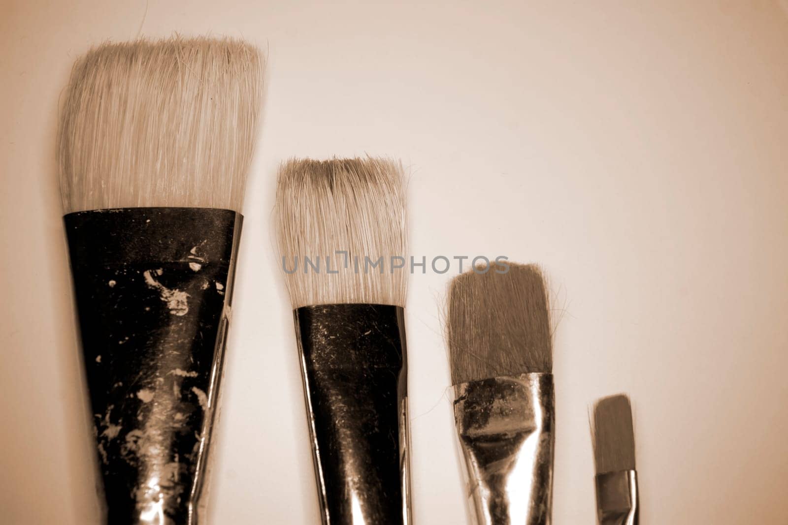 collection of various artists brushes in all sizes on a canvas background in sepia
