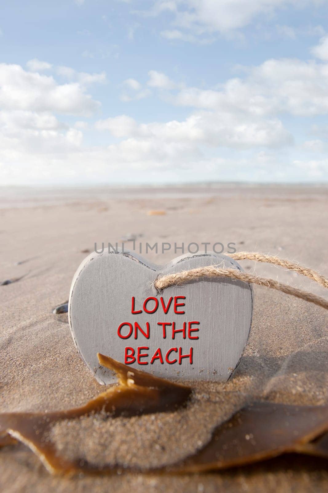 single wooden love heart in the sand on a wild Atlantic way Irish beach in summer with copy space