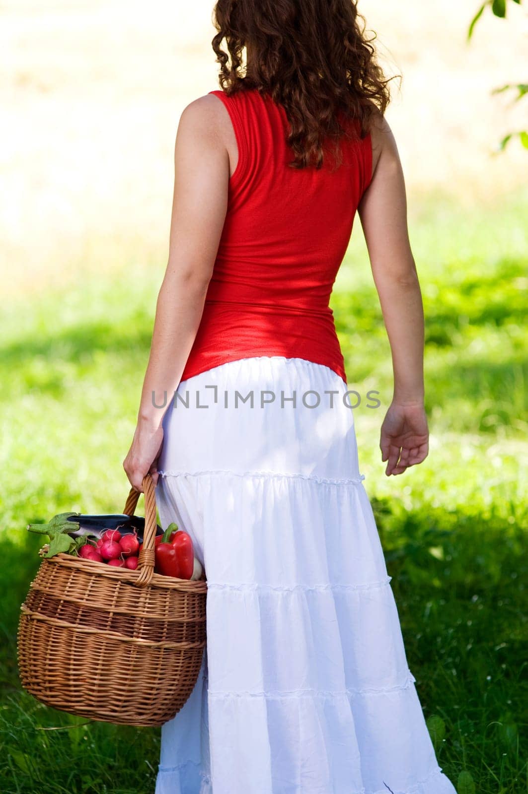 Young woman holding basket filled fresh vegetables