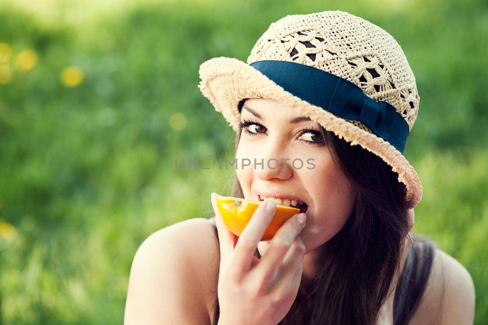 Beautiful woman eating orange on meadow