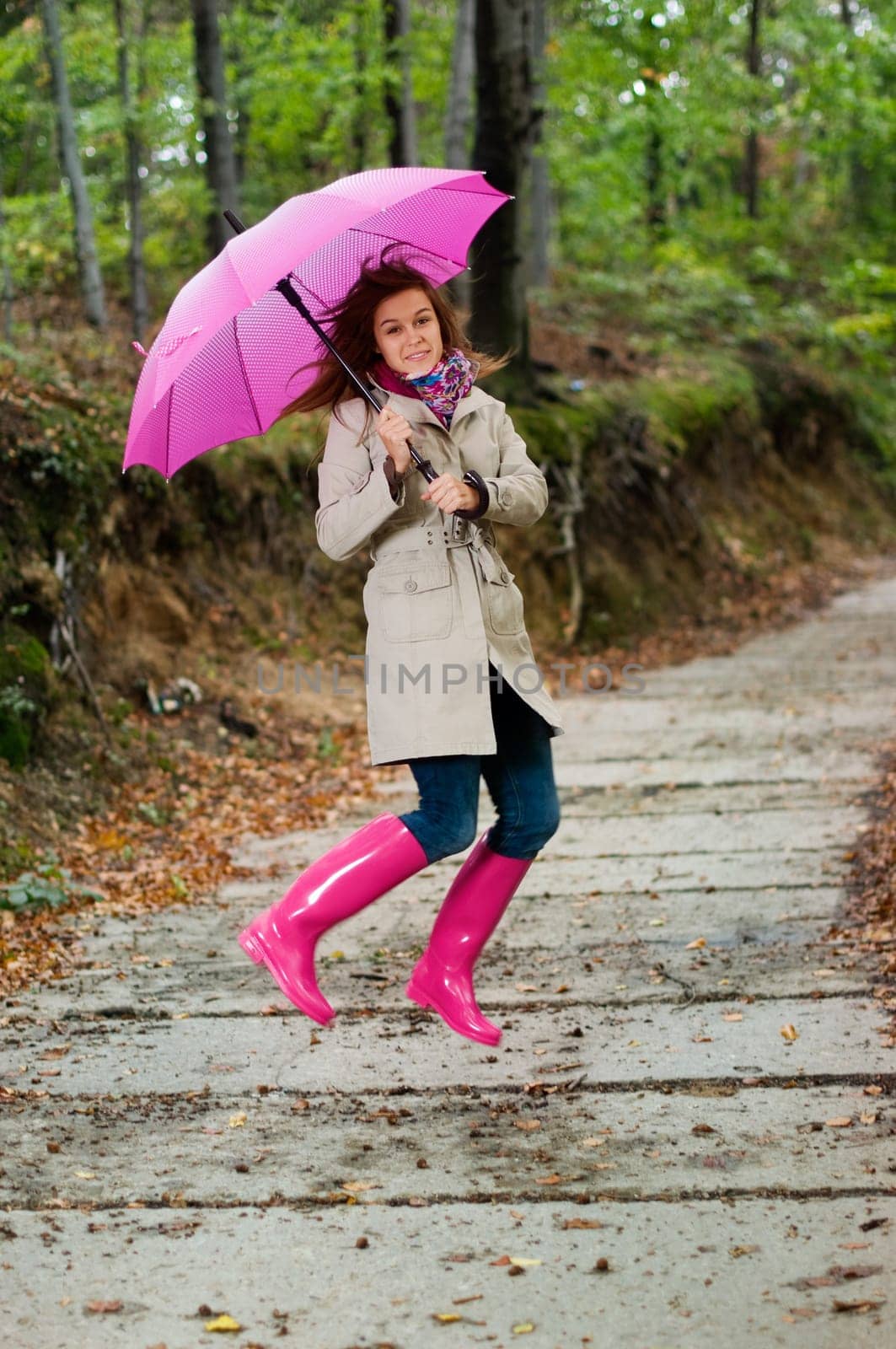 Cute young woman jumping with umbrella