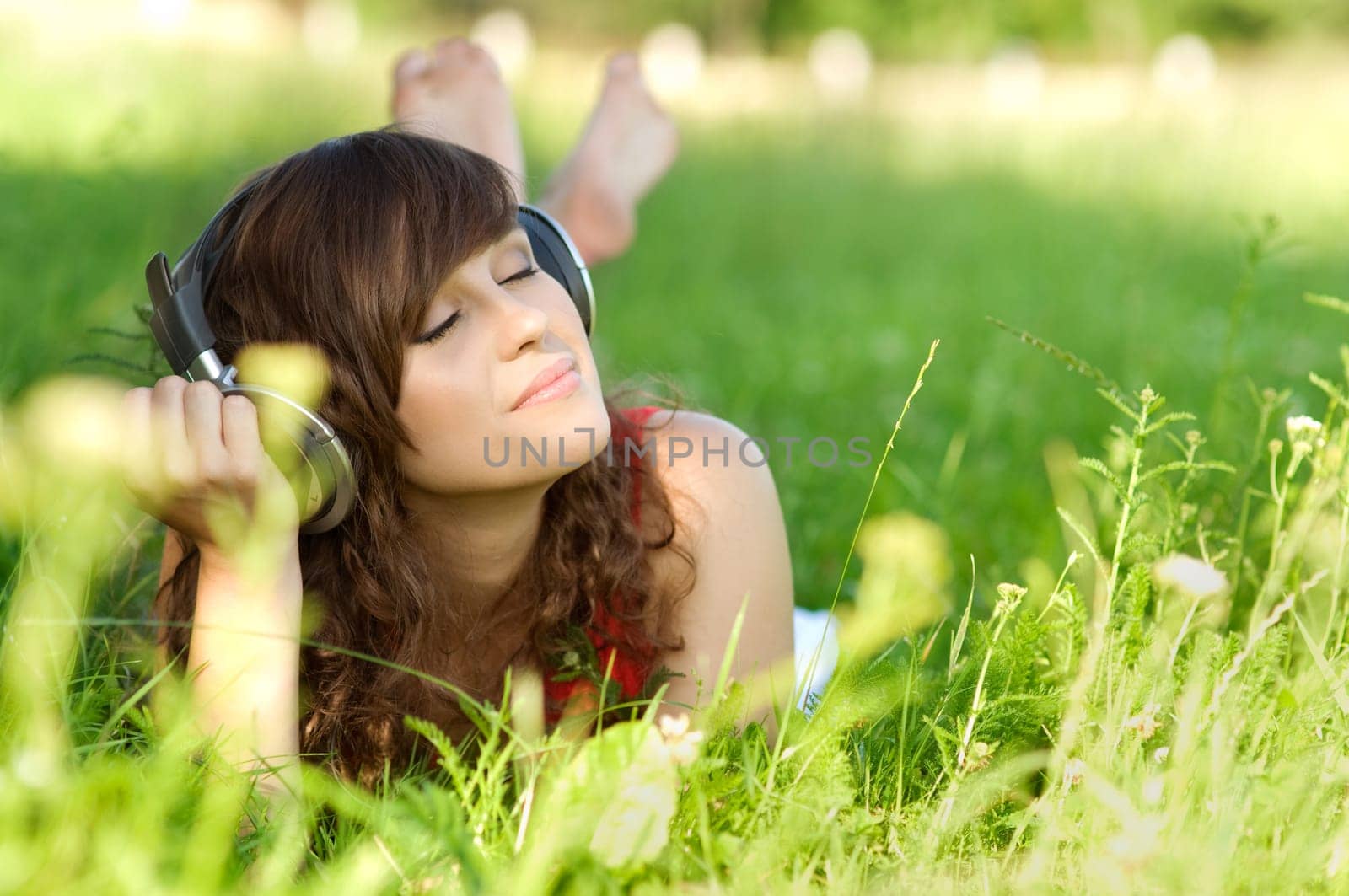 Young woman listening music on grass