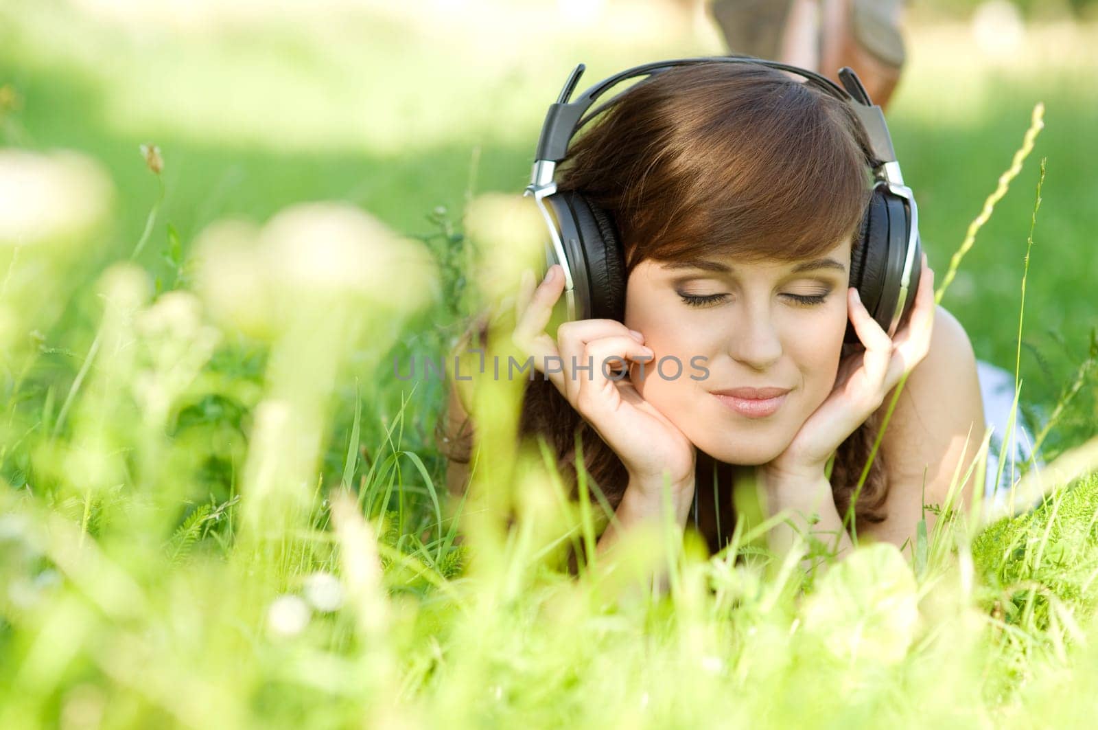 Young woman listening music on grass