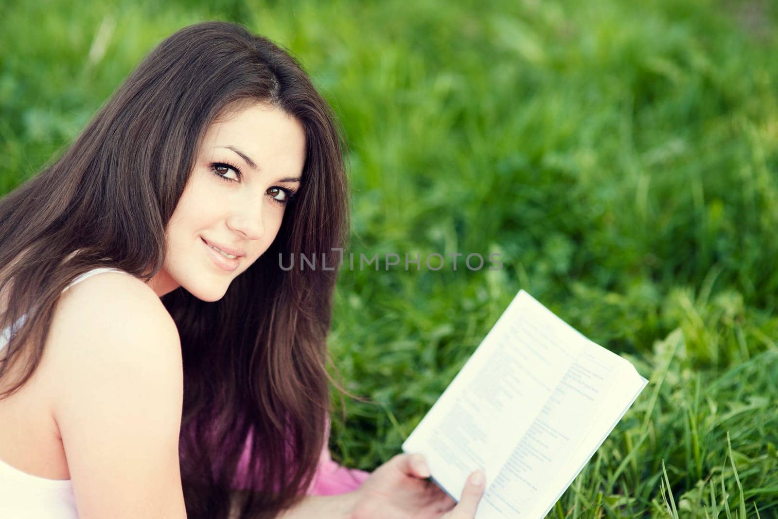 Young woman reading a book on meadow