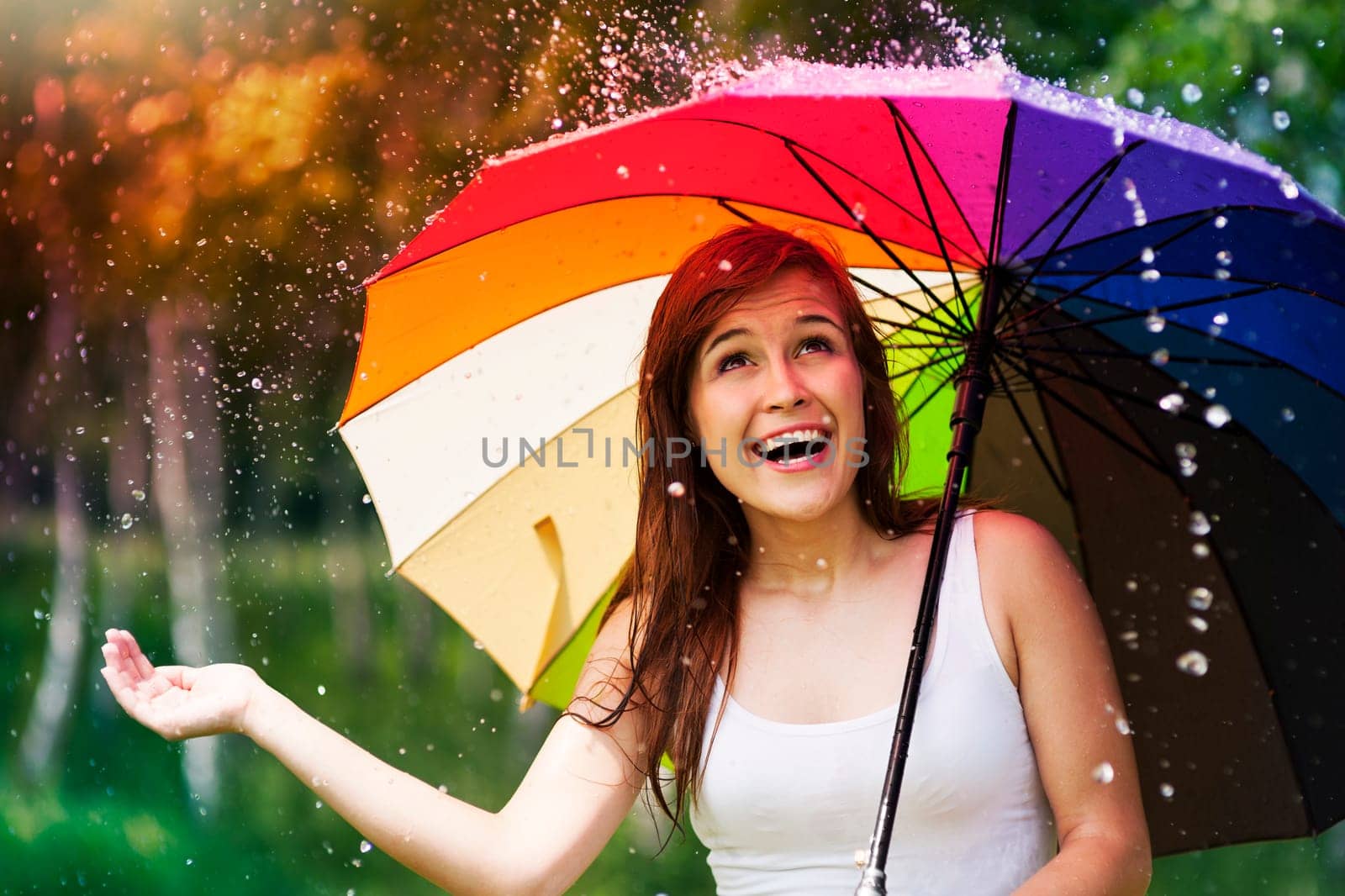 Surprised woman with umbrella during summer rain