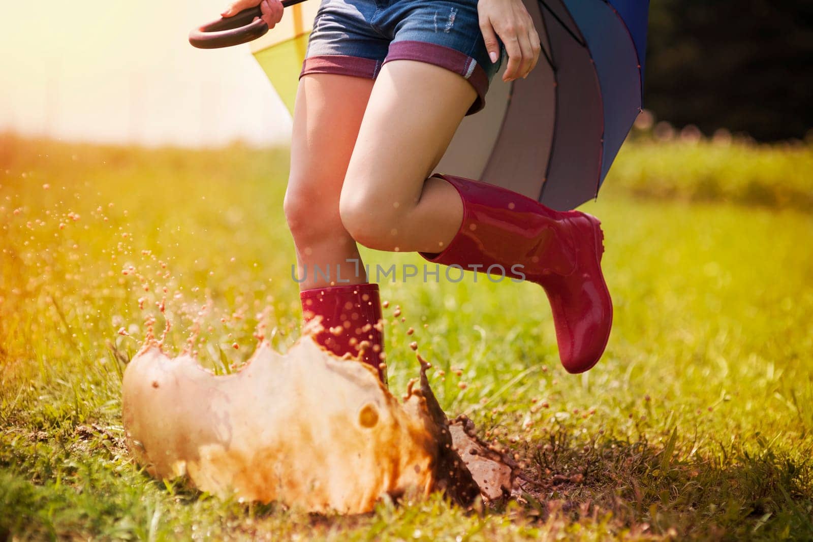 Jumping woman with umbrella and rubber boots