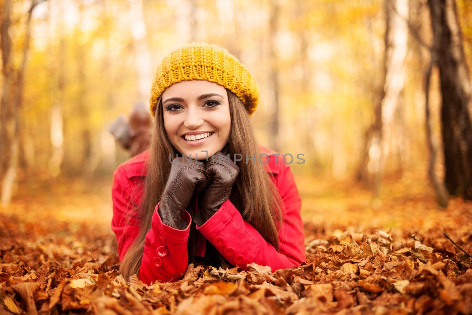 Smiling woman lying down on autumn leaves