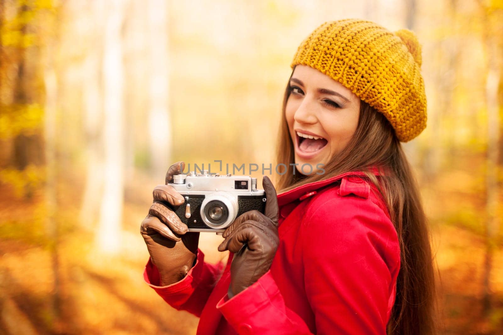 Winking woman taking photo by retro camera